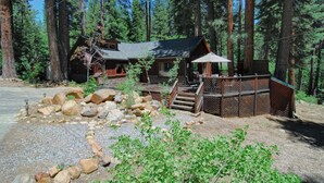 A cabin with a deck, surrounded by a forest. - The Bernstein Bear Cabin (Kings Beach)