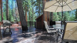 A covered deck with a grill, chairs, and an umbrella. - The Bernstein Bear Cabin (Kings Beach)