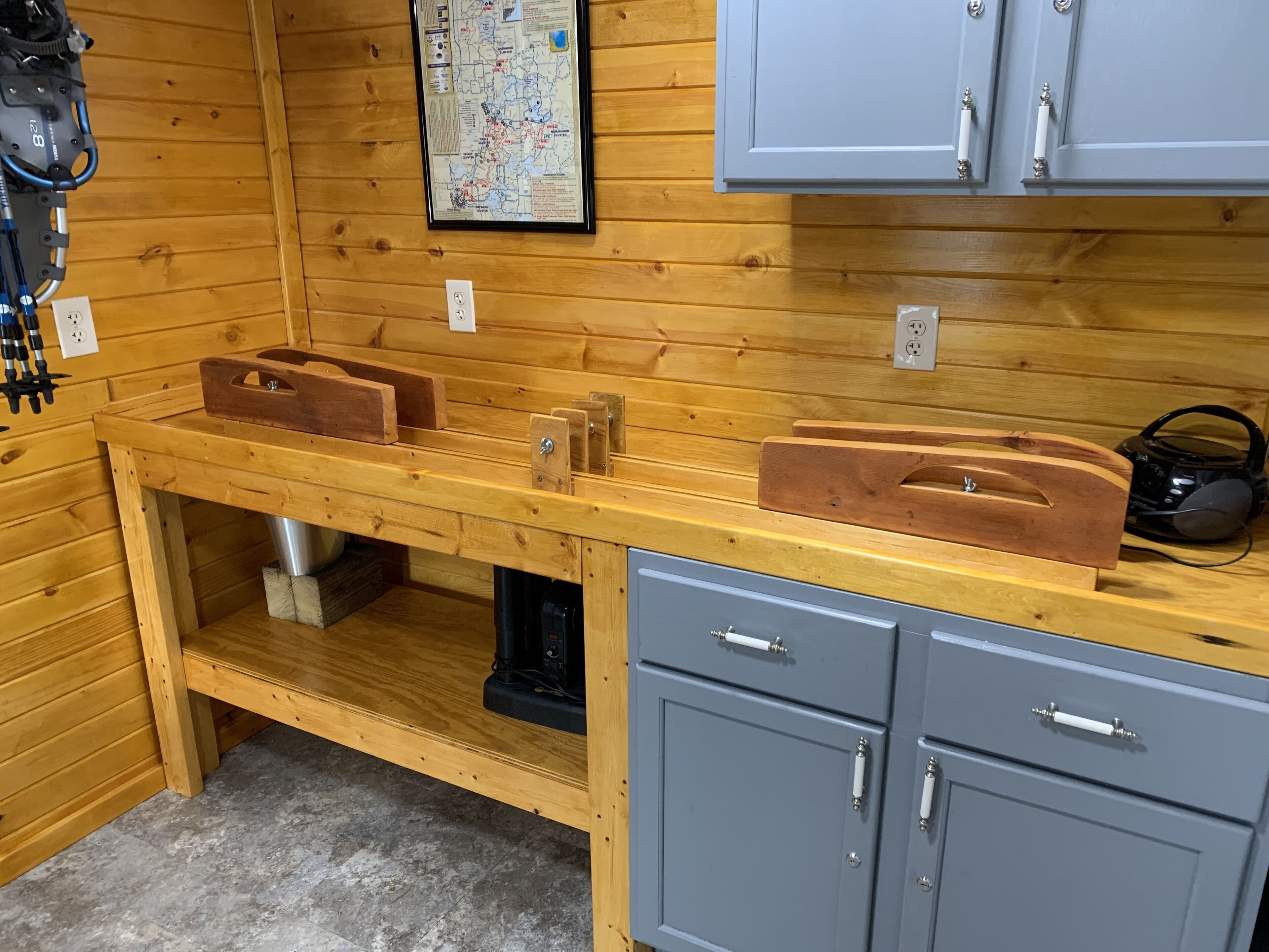 A wooden cabin interior with a kitchenette, cabinets, and a map on the wall.