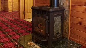 Una estufa de leña en una habitación con piso de cuadros y paredes de madera.