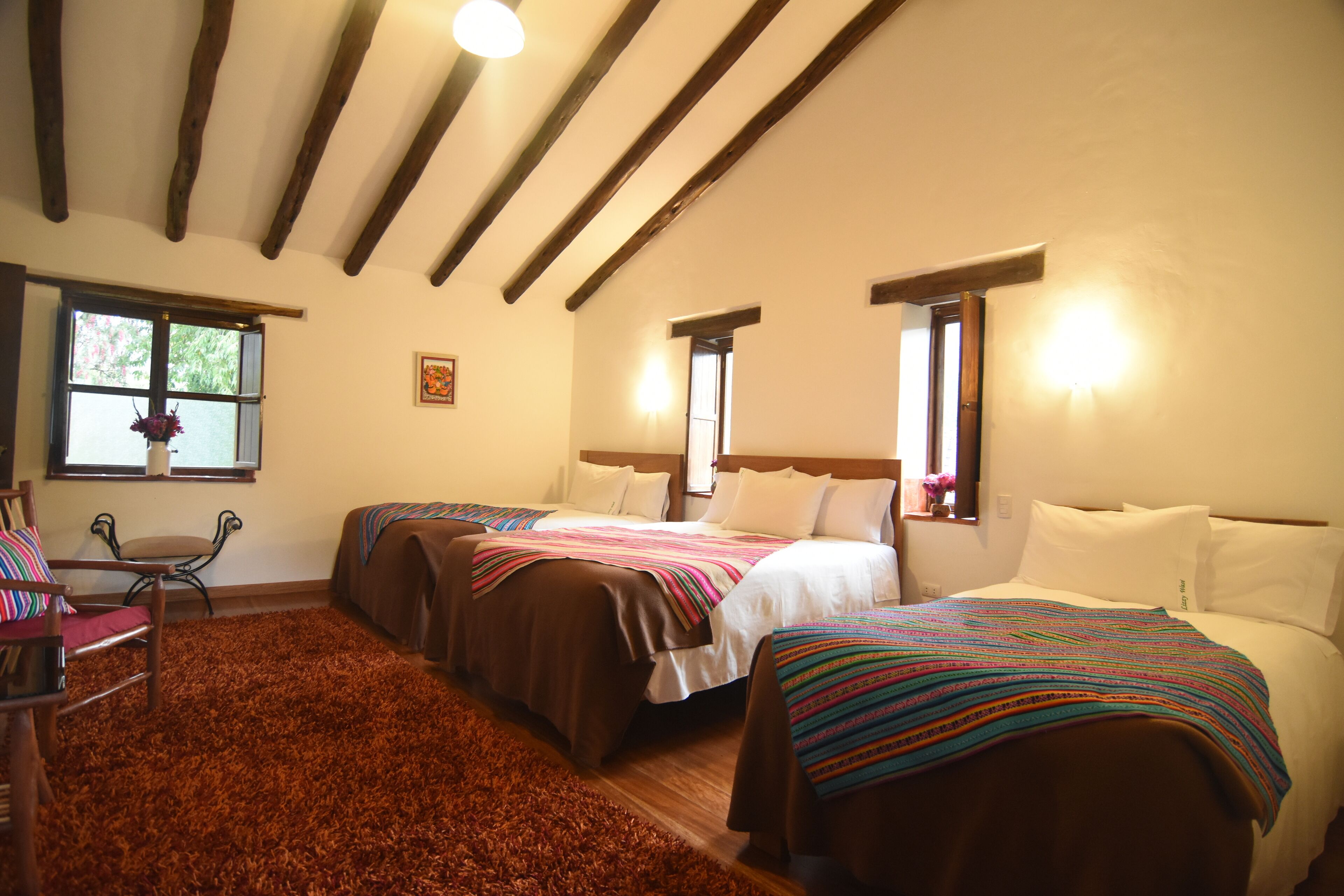 Une chambre avec deux lits, un plafond en bois, une fenêtre donnant sur un beau paysage et une chaise.