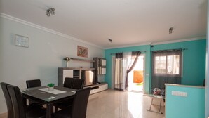 Een moderne woonkamer met een eethoek, keuken en een schuifpui naar een balkon.