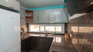 Een moderne keuken met een Bosch koelkast, donkere kastjes, een granieten aanrechtblad en een raam voor natuurlijk licht.