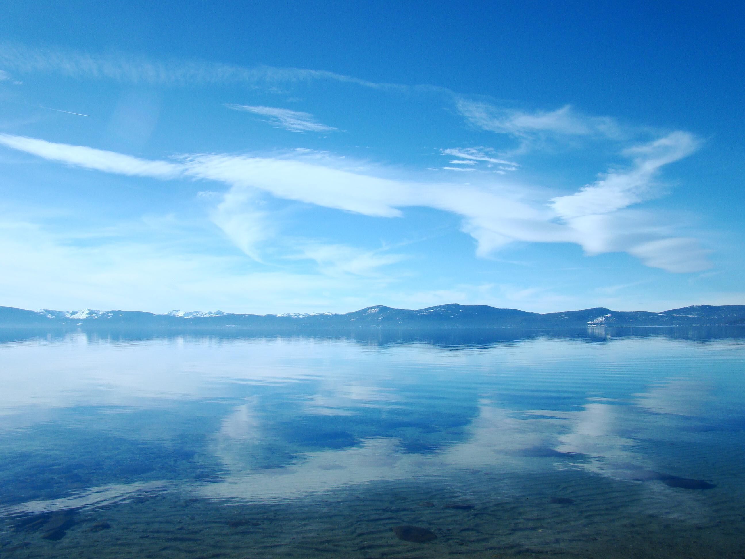 A clear lake with a mountain range in the background.