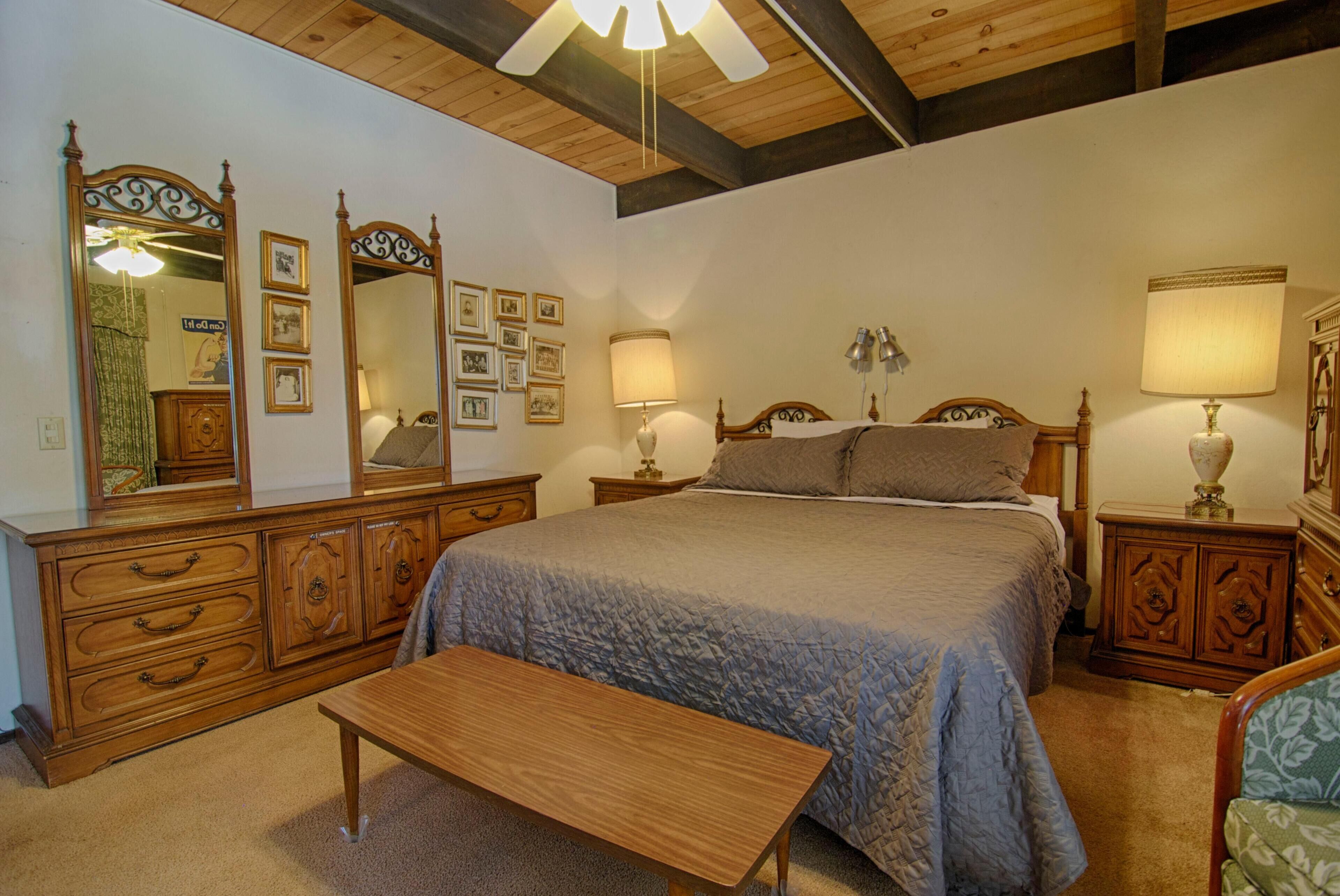 Een slaapkamer met een groot bed, een houten dressoir en een bankje.