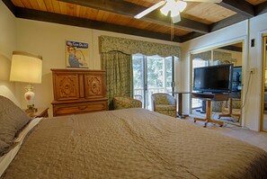 A bedroom with a large bed, a wooden dresser, a television on a stand, and a window with curtains. - Vidor Village (Kings Beach)