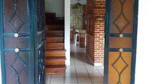 A hallway with a tiled floor, a staircase, and a door with a decorative metal design.