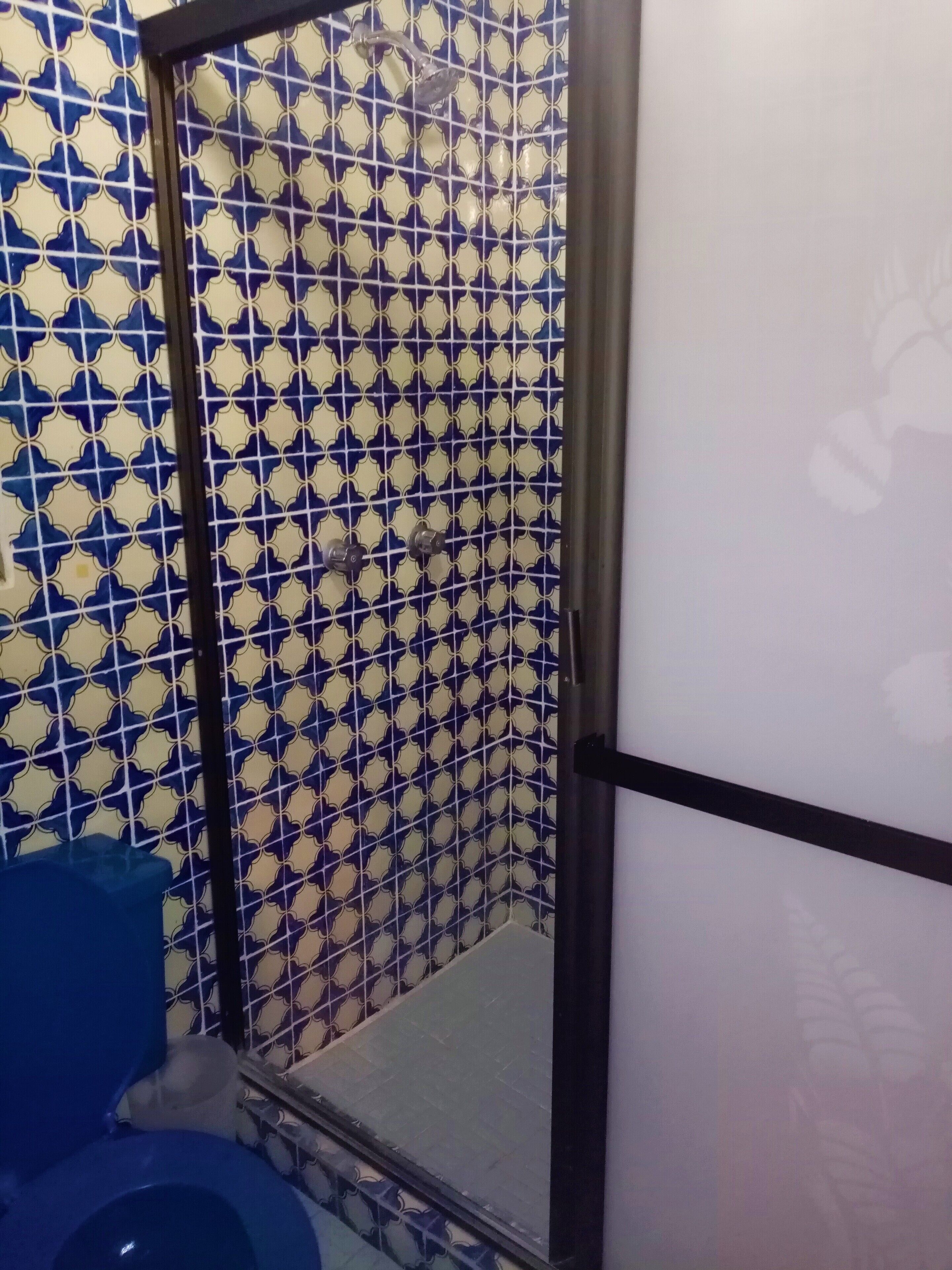 Een badkamer met een betegelde muur met een patroon, een toilet en een douche.