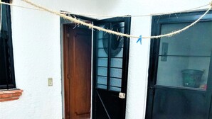 A tiled patio area with a black door and window, a visible manhole cover, and a rope barrier.