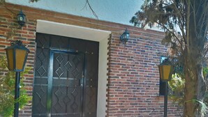A brick building with a decorative metal door and two wall-mounted lanterns.