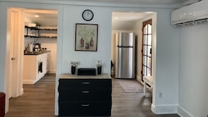 Una cocina moderna con un refrigerador de acero inoxidable, un reloj en la pared y un cuadro sobre la encimera.