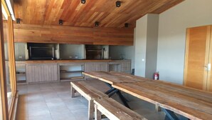 A modern kitchen with wooden cabinetry, a large wooden table, and built-in appliances.