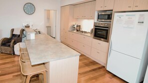 Eine moderne Küche mit einer zentralen Kochinsel, Holzschränken, einem Einbauofen und einem Kühlschrank.