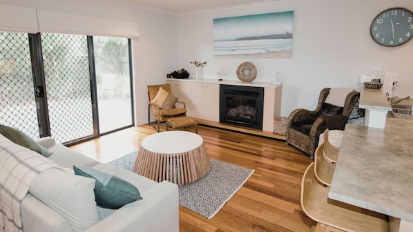 A modern living room with a fireplace, a dining area, and a large window with a view.