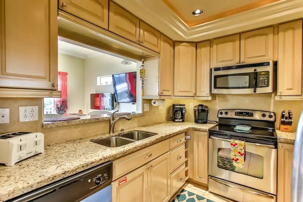 A compact kitchen with a microwave, stove, sink, and a dishwasher.