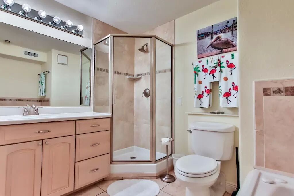 A bathroom with a glass-enclosed shower, a toilet, and a vanity with drawers.