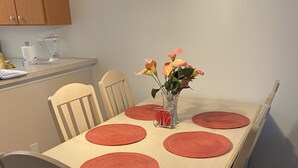 Ein Esstisch mit sechs Stühlen, eine Vase mit Blumen und ein Mixer auf der Arbeitsfläche.