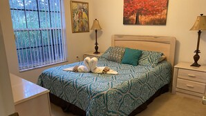 Ein Schlafzimmer mit einem Bett, zwei Nachttischen, einem Fenster mit Jalousien und zwei Wandleuchten.