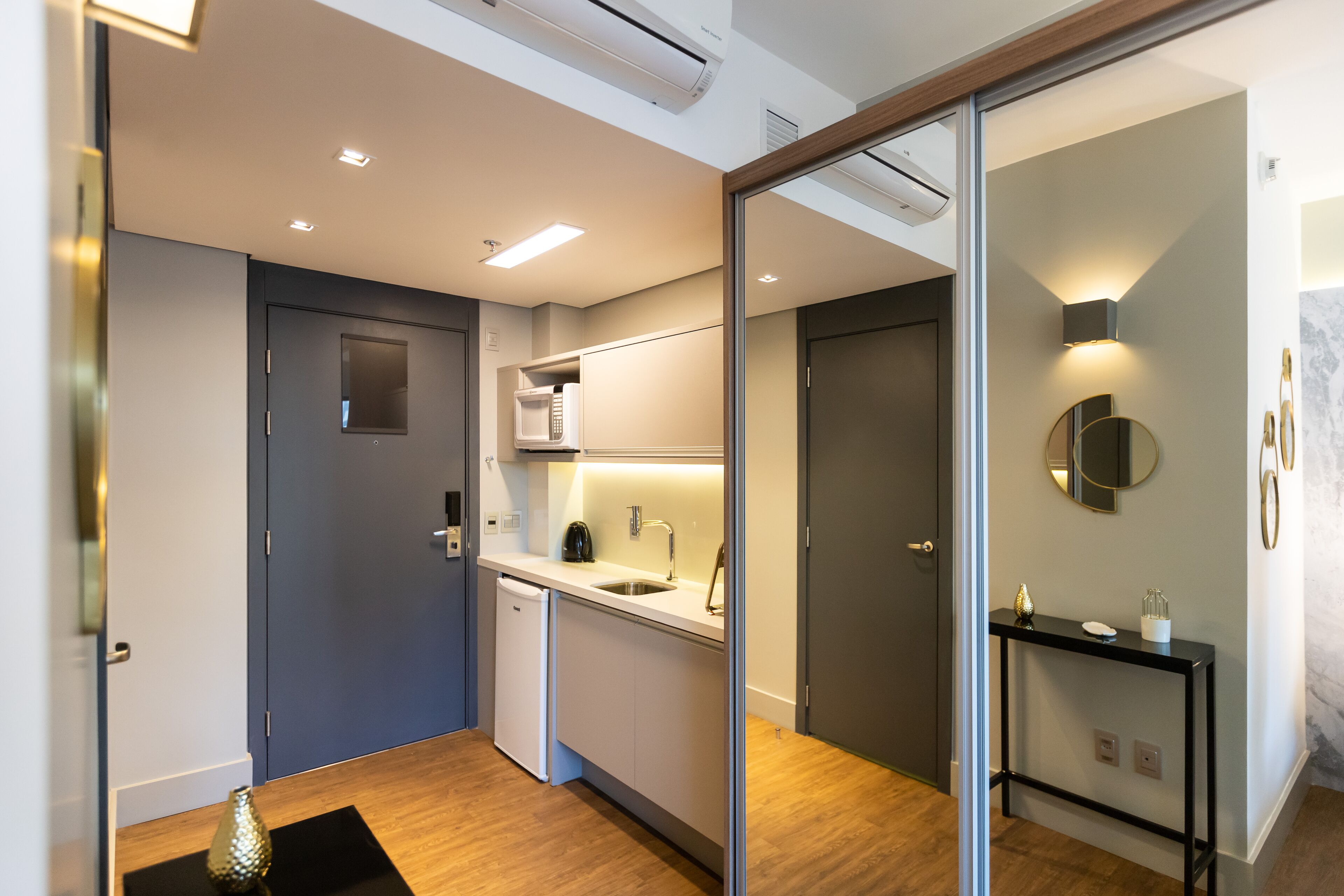 A modern kitchen with a microwave, sink, and a black console table.