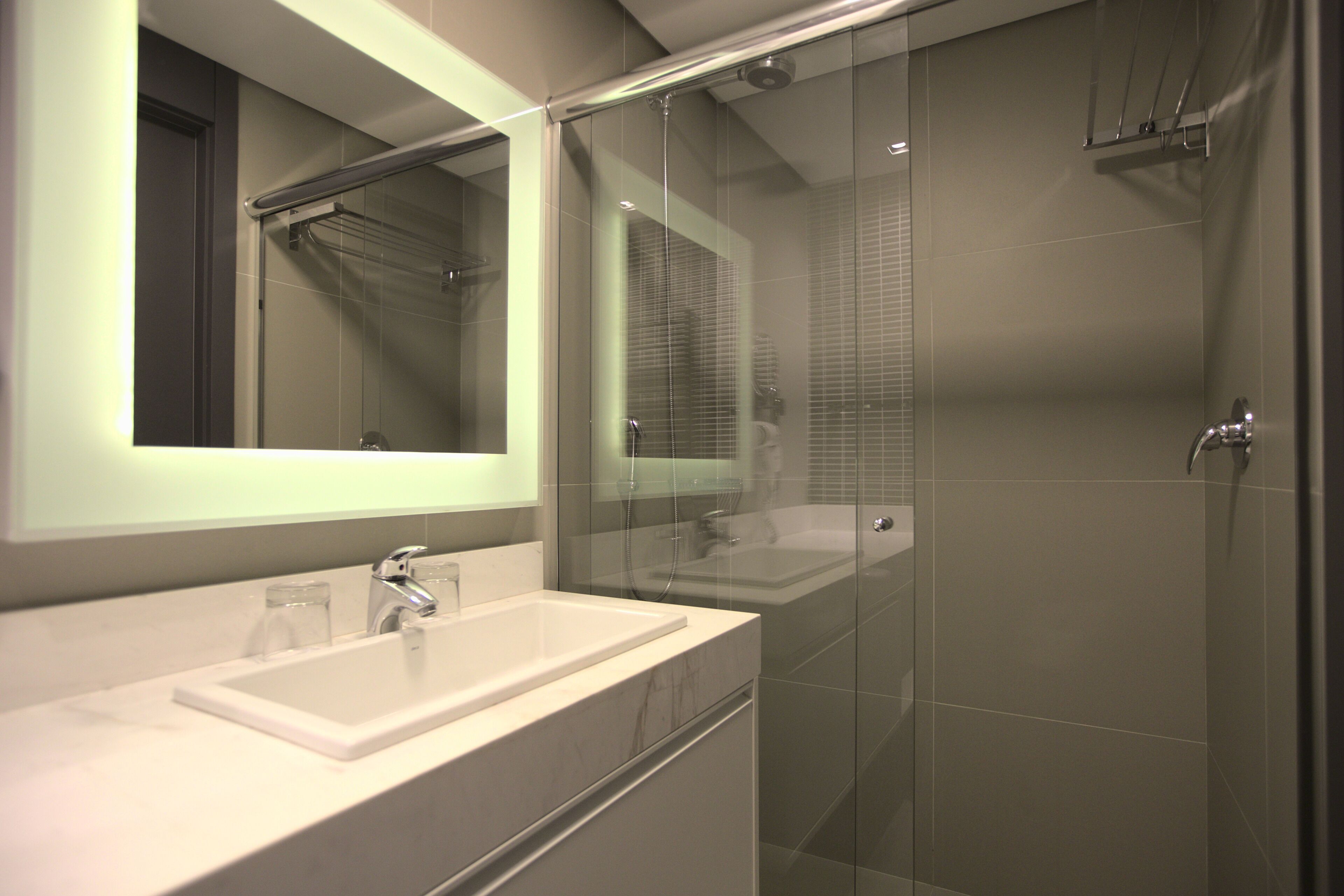Une salle de bain moderne avec une douche à parois de verre, un lavabo blanc et un grand miroir.