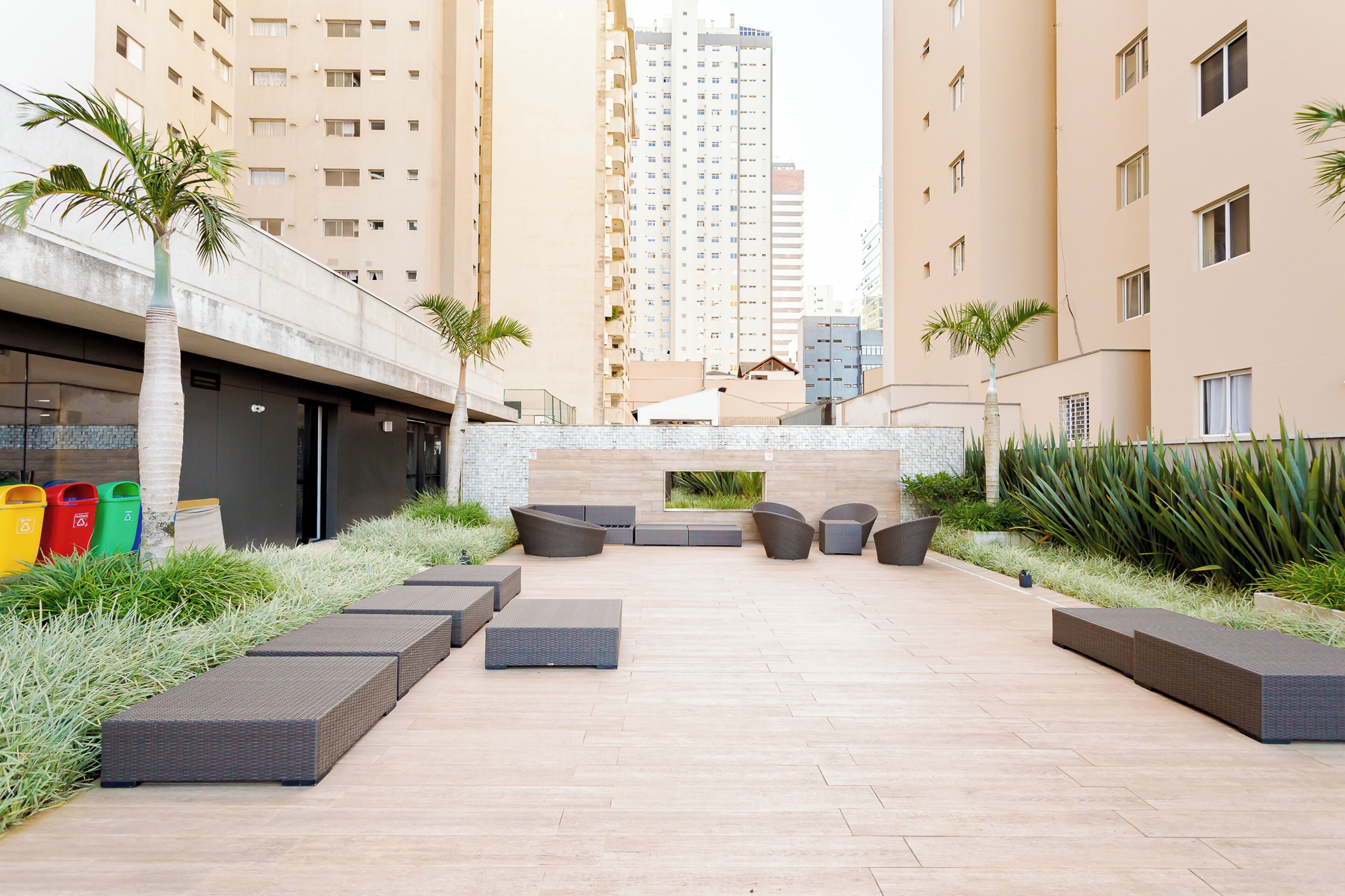 An outdoor seating area with modern furniture, surrounded by tall buildings and greenery.