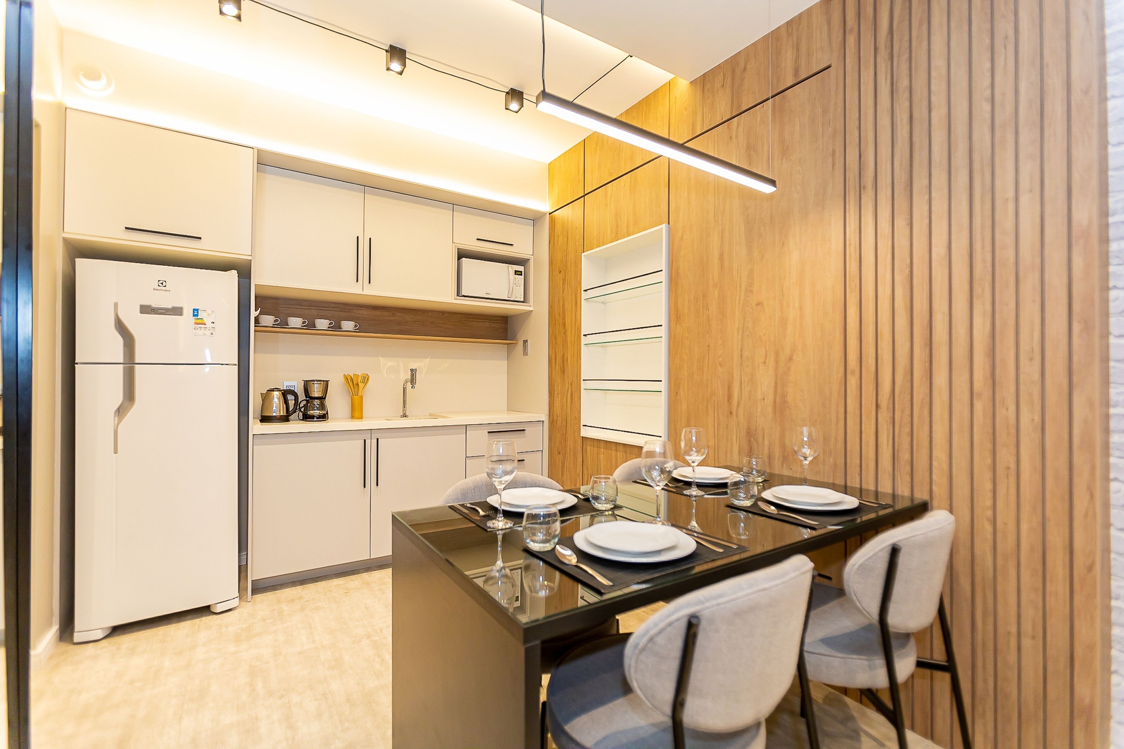Una cocina moderna con comedor, que incluye un refrigerador, microondas y paneles de madera.