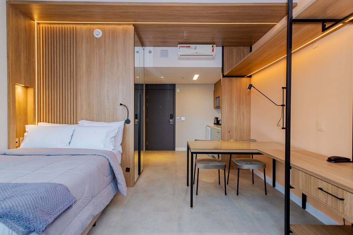 Une chambre moderne comprenant un lit, une table de chevet et un espace bureau avec une chaise.