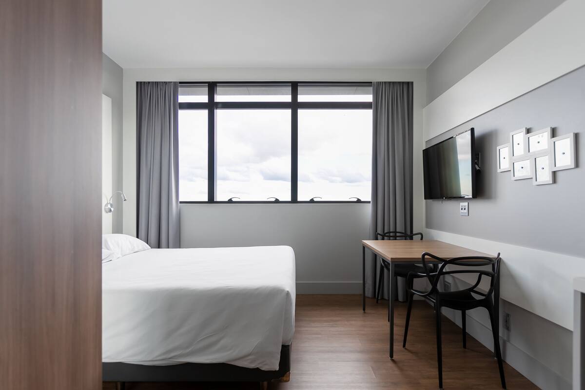 Une chambre d’hôtel moderne équipée d’un lit, d’un bureau et d’une télévision.
