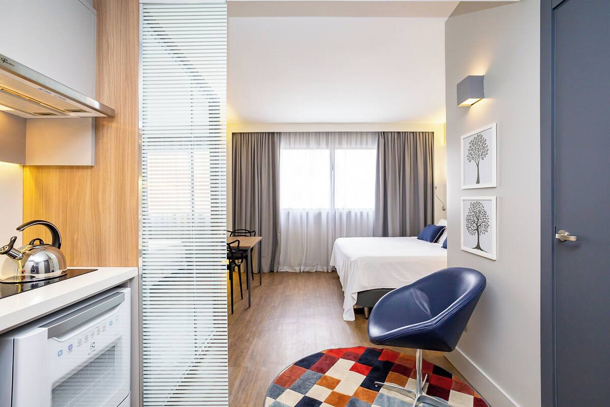 Une chambre d’hôtel équipée d’un lit, d’un bureau, d’une chaise, d’une bouilloire et d’un radiateur.