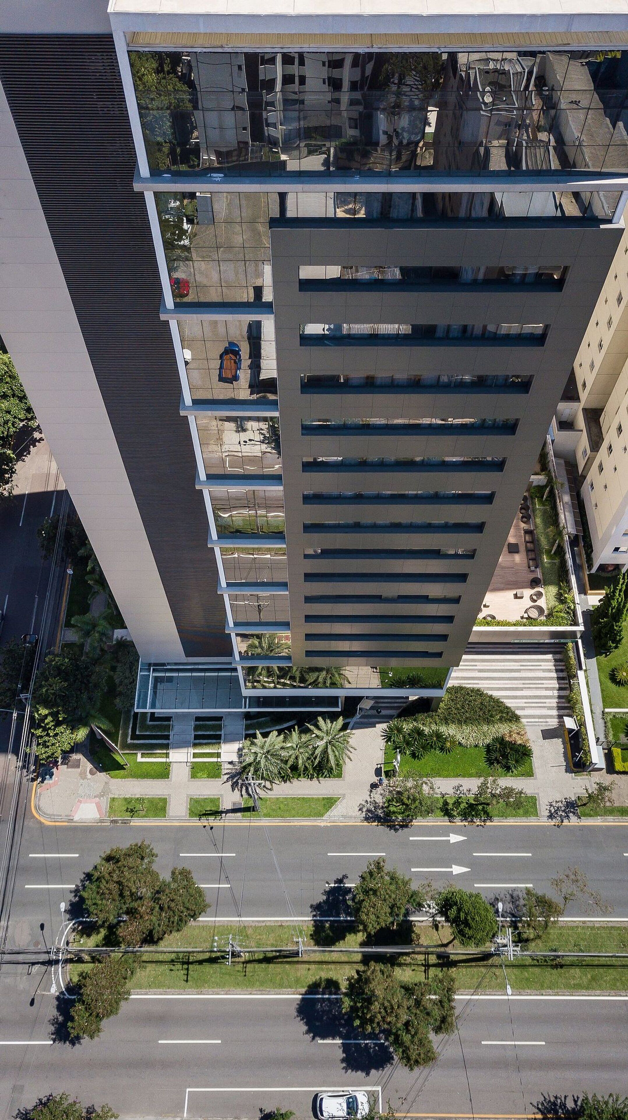 A high-rise building with a modern design, featuring multiple balconies and a rooftop garden.