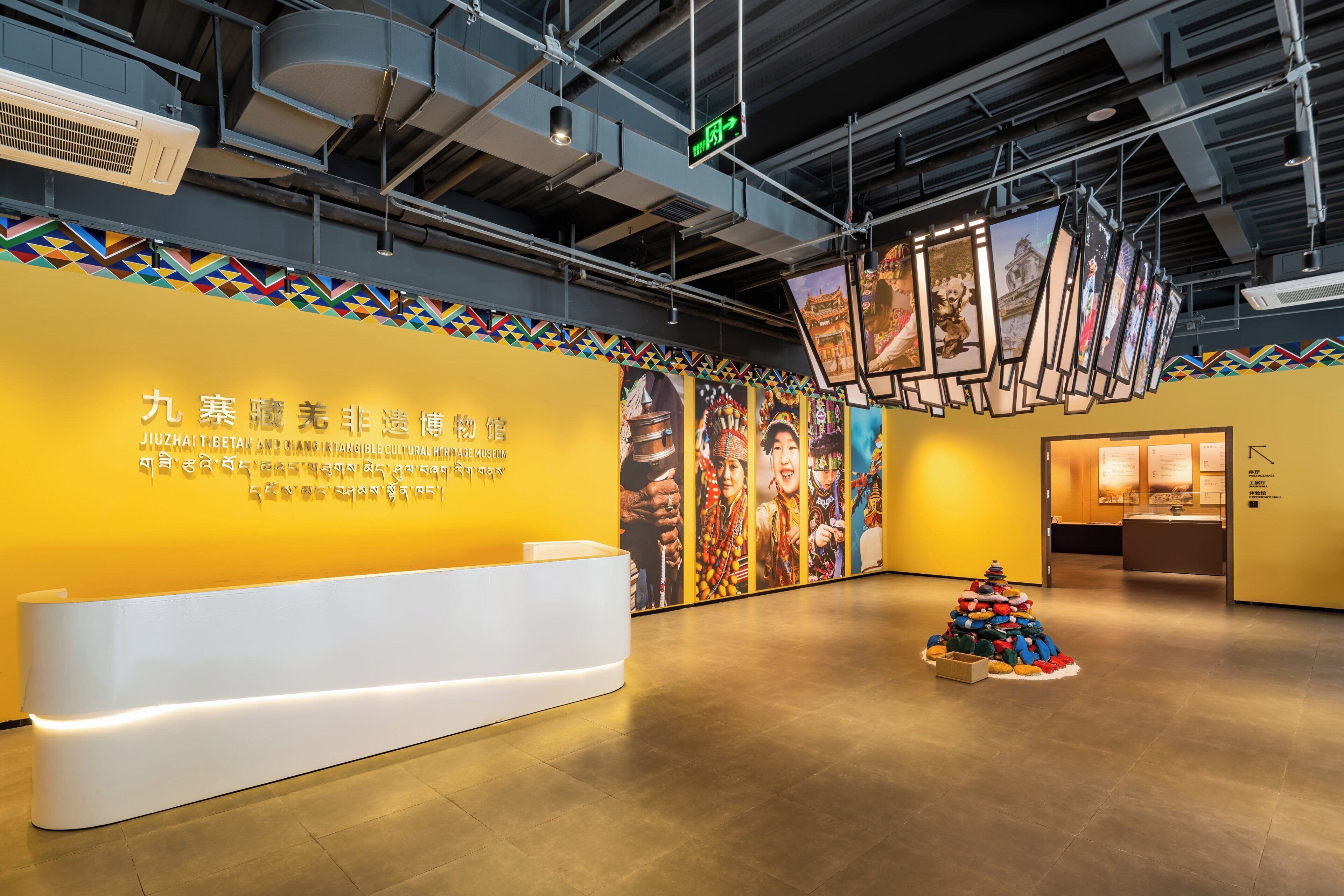 A reception area with a modern design, featuring a reception desk, a wall with cultural artwork, and a unique sculpture.