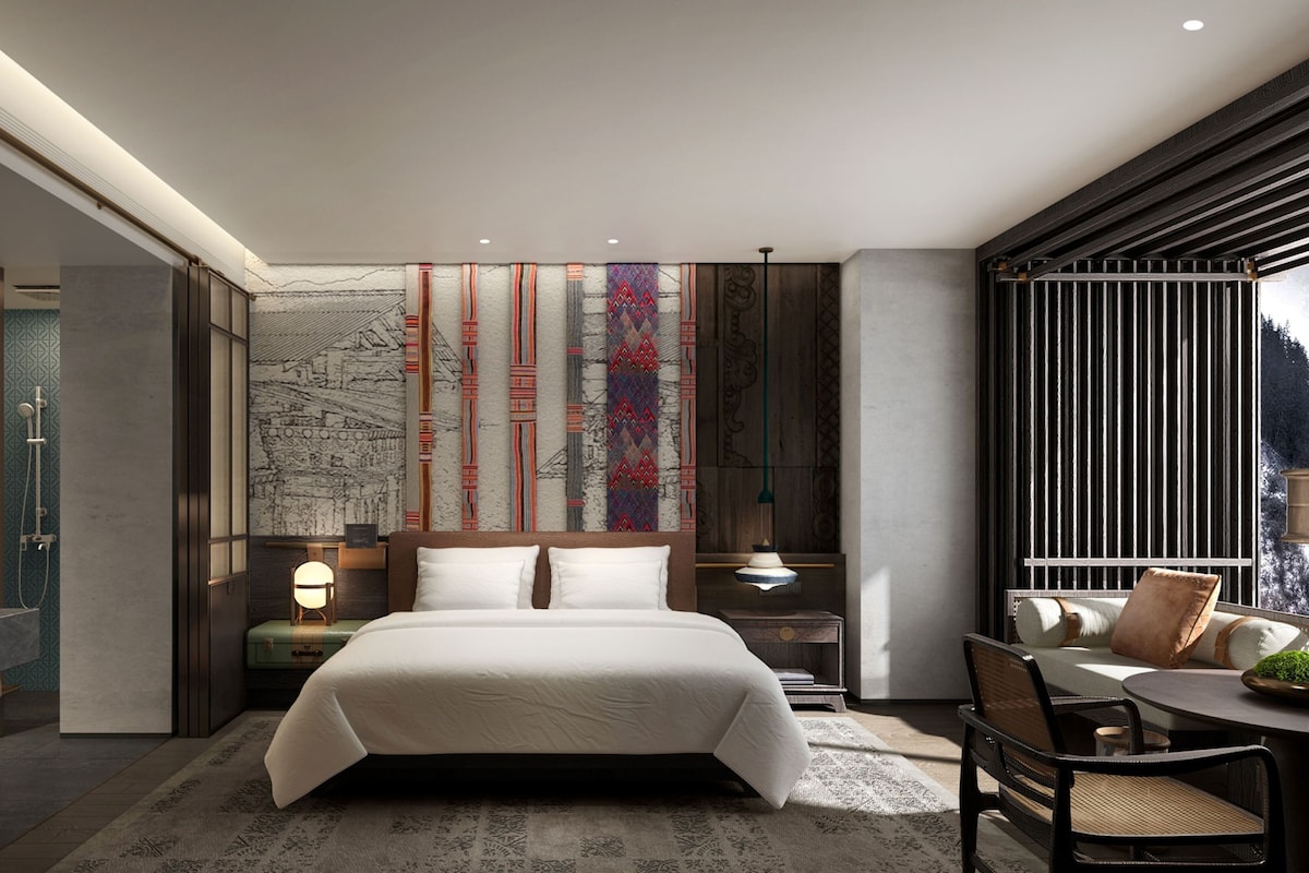 Ein modernes Hotelzimmer mit einem großen Bett, einem Schreibtisch und einer Sitzecke.