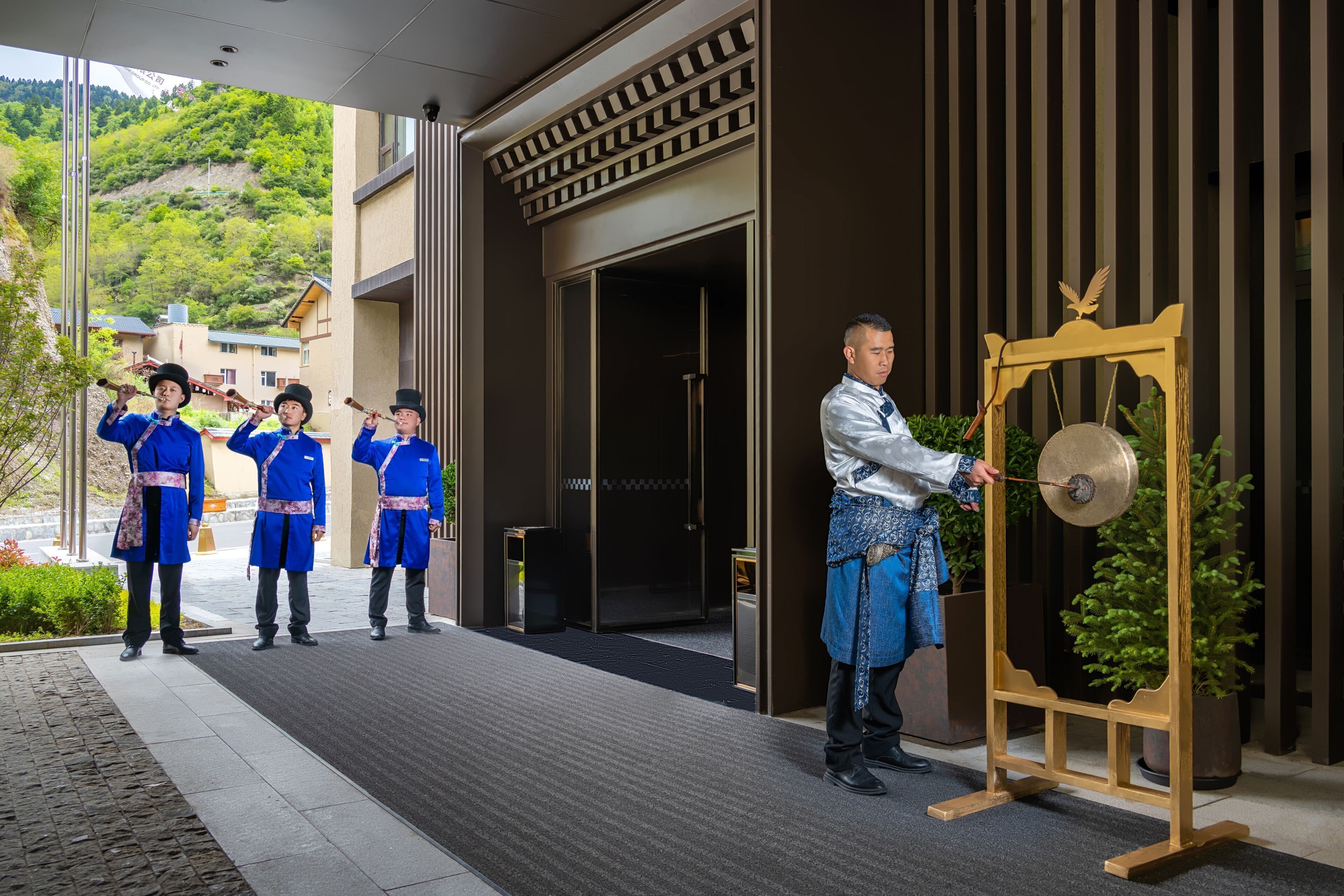 Een hotelingang met een traditionele gong en bewaakers in uniform.