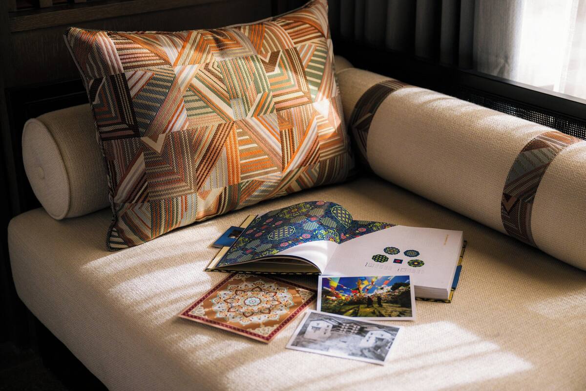 Un canapé agrémenté de coussins à motifs, un livre et quelques objets décoratifs.
