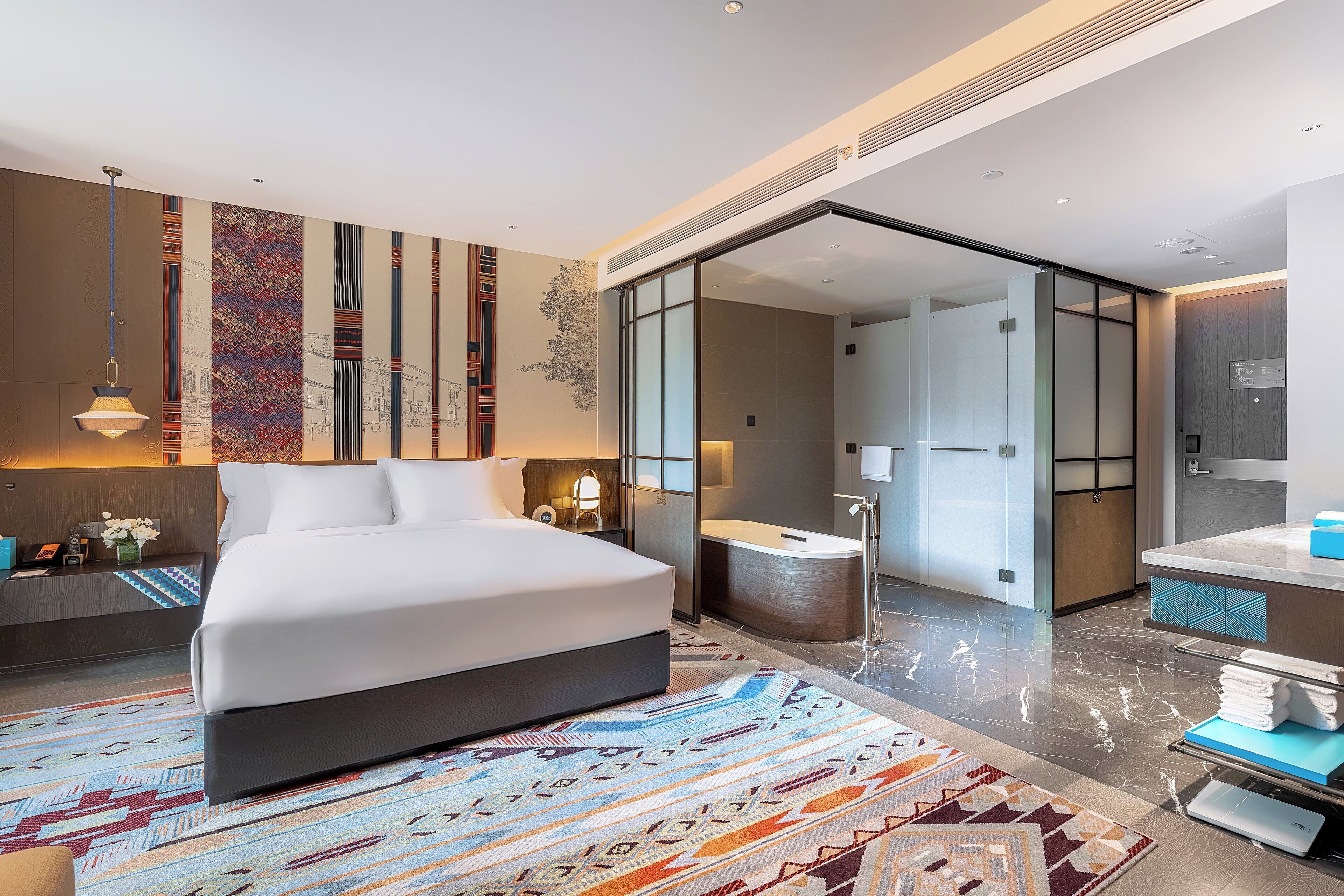 A modern hotel room with a large bed, a bathroom with a bathtub, and a shower.