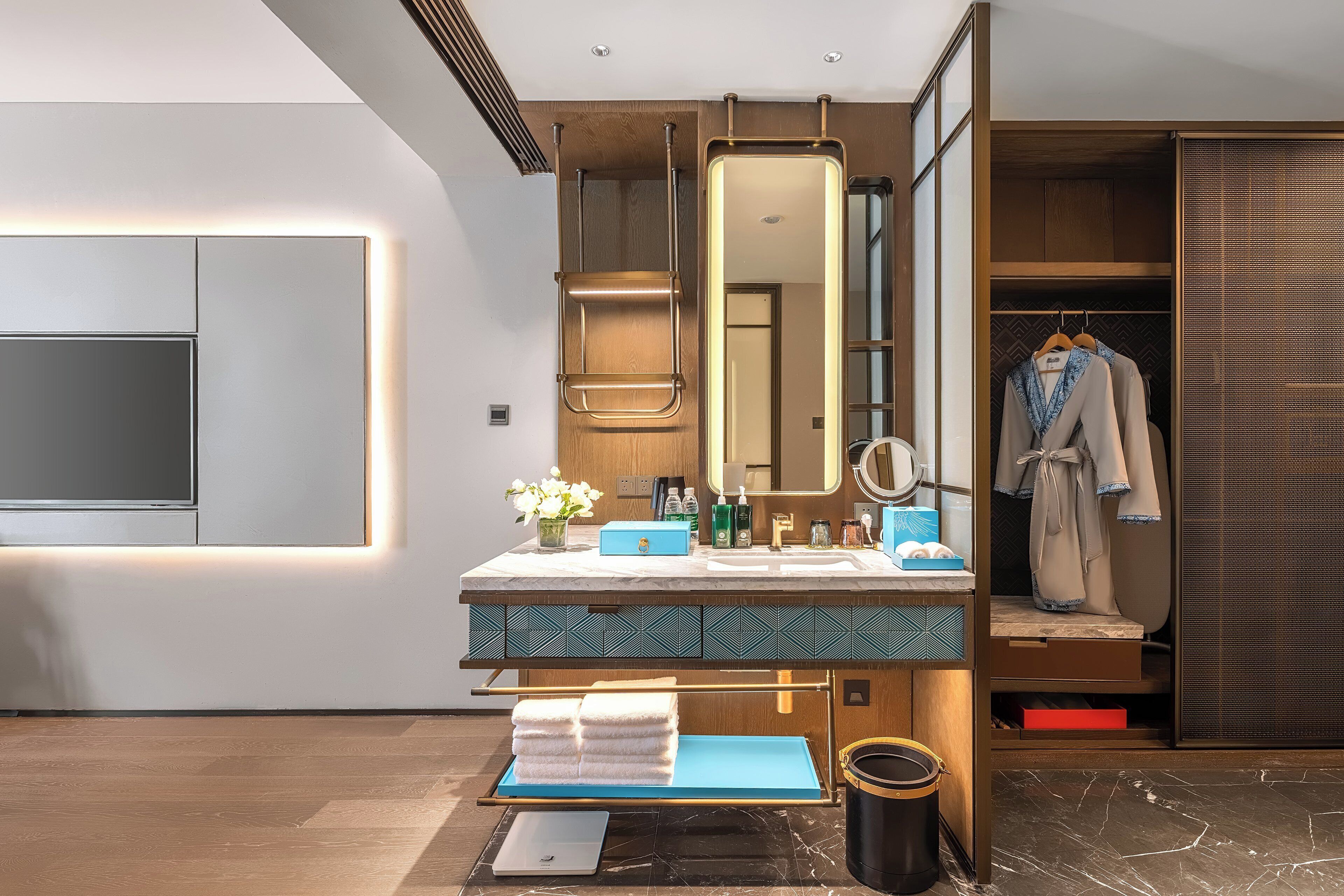 Un baño moderno con un espejo grande, un tocador con encimera de mármol y un vestidor con perchero.