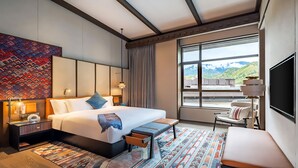 Ein modernes Hotelzimmer mit einem großen Bett, Nachttischen, einem Schreibtisch, einem Sessel und einem Fernseher.