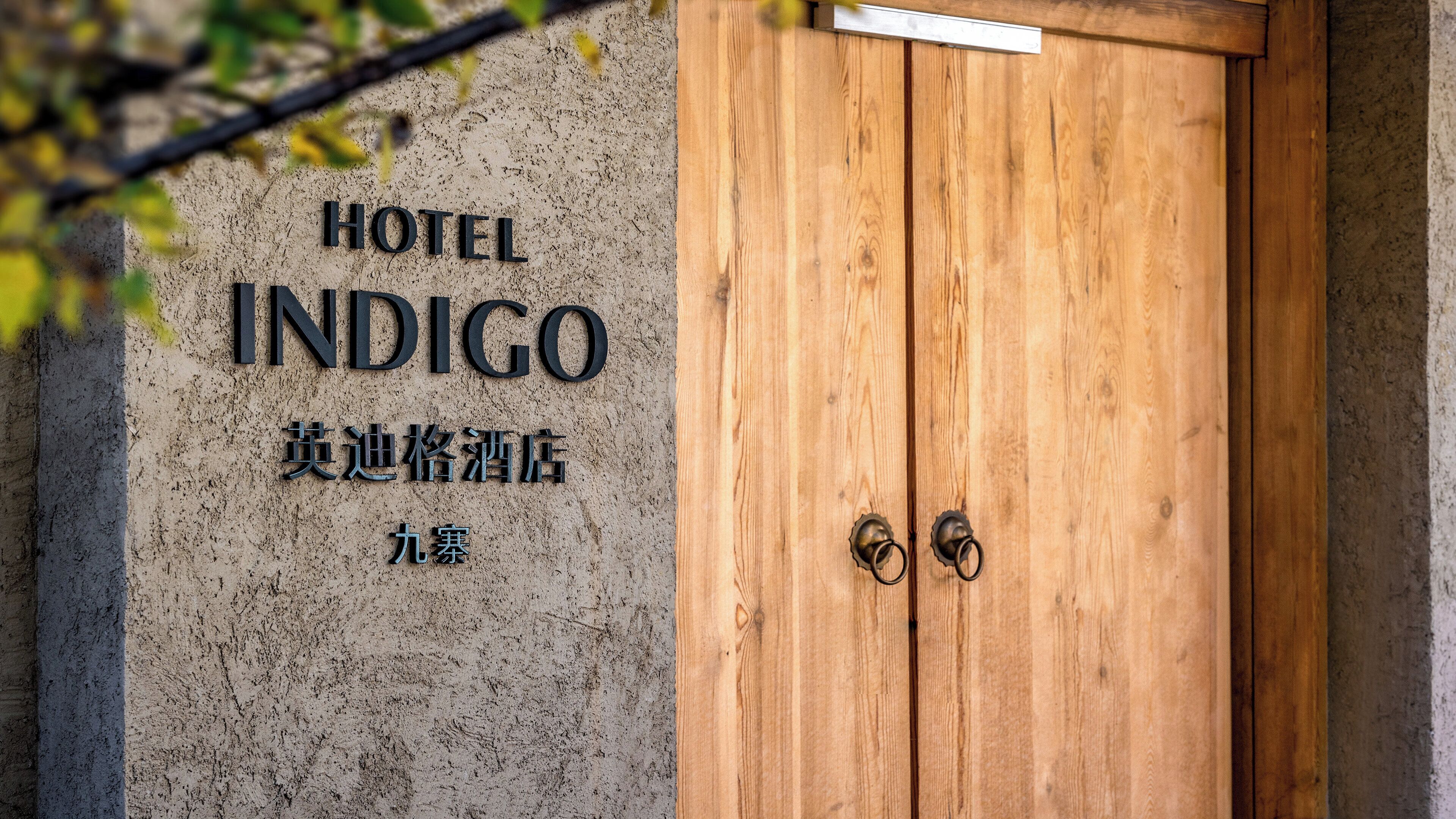 A wooden door with a sign above it that reads 'HOTEL INDIGO' and some Chinese characters.