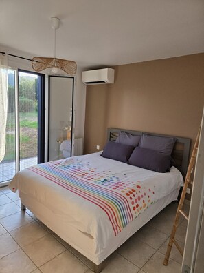 A bedroom with a bed, a window, an air conditioning unit, and a door.