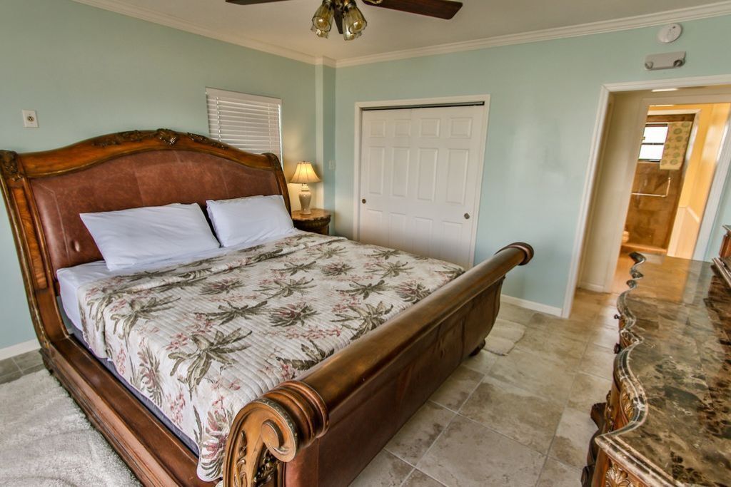 A bedroom with a wooden bed, a white door, and a ceiling fan.