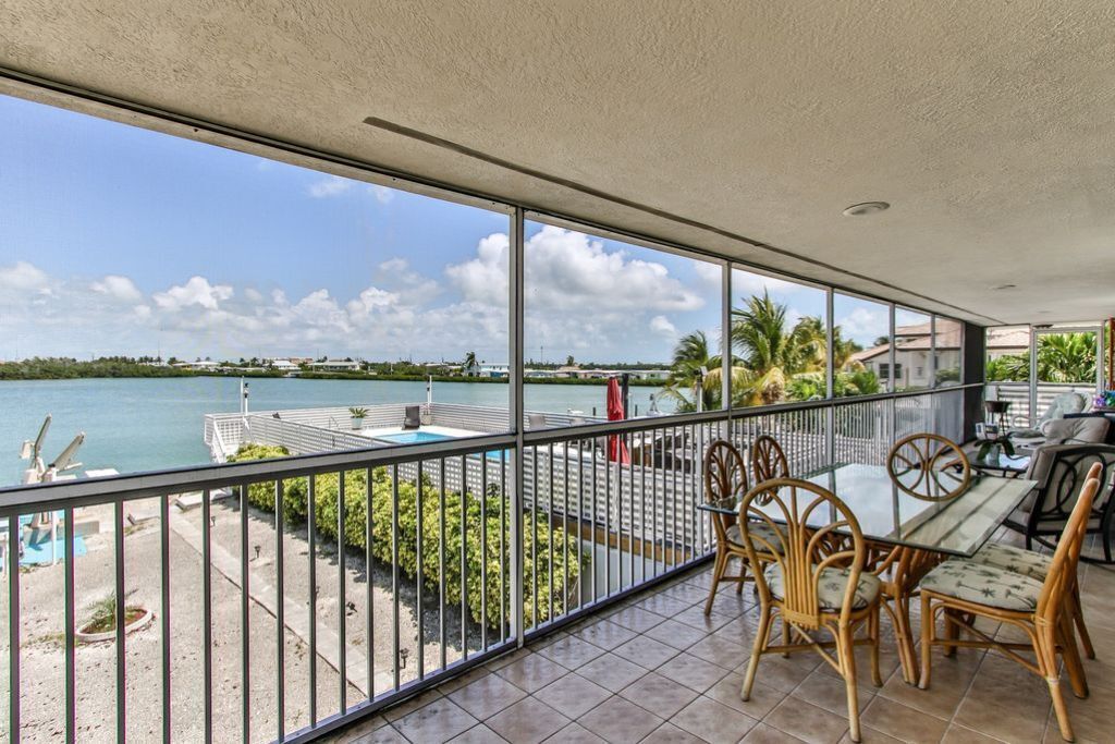 Un balcon donnant sur une piscine et un plan d’eau.