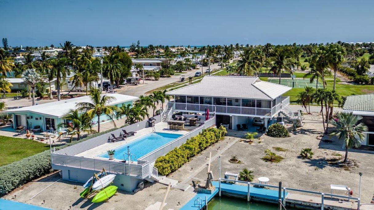 A resort with a swimming pool, a tennis court, and a beach area.