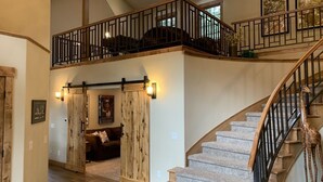 A spacious interior with a high ceiling, a staircase, and a second-floor balcony.