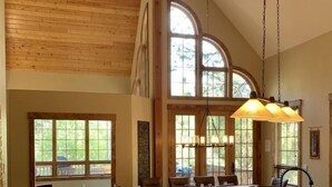 A spacious kitchen with a large island, wooden beams, and large windows.