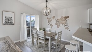 Un coin repas avec une table et des chaises en bois, un lustre et une carte du monde accrochée au mur.