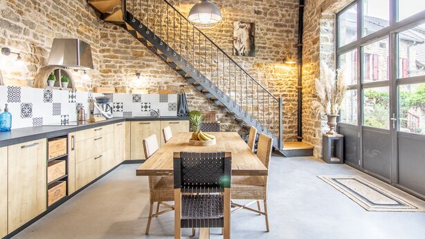 Una cocina moderna con una mesa de madera, sillas y una escalera que lleva a un nivel superior.