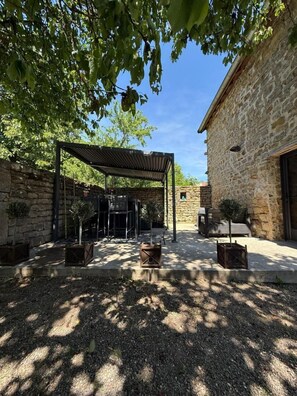 A courtyard with a pergola, stone walls, and potted plants.