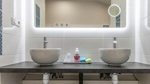 Un baño moderno con dos lavamanos, un espejo grande y un perchero para toallas.