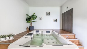 Un espace de spa moderne doté d’un grand jacuzzi, d’un plancher en bois et d’un aménagement minimaliste.
