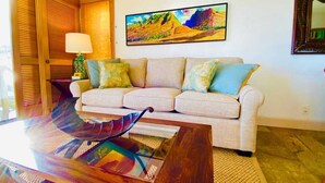Ein Wohnzimmer mit Sofa, Couchtisch, Gemälde und Lampe.